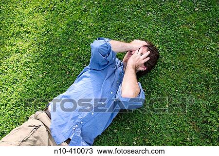 Young man lying on the grass at a park in Hartford, Connecticut, USA, covering his face. View Large Photo Image Stock Image - Young man lying on the grass at a park in Hartford, Connecticut, USA, covering his face.. Fotosearch