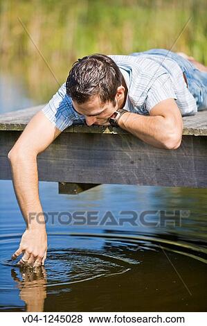 Young man on a footbridge at a lake contemplating View Large Photo Image Stock Photo - Young man on a footbridge at a lake contemplating. Fotosearch
