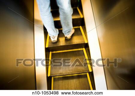 Stock Photo - Young man on an escalator. Fotosearch