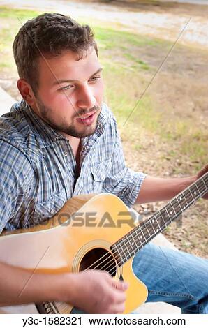 Young man playing guitar View Large Photo Image Stock Image - Young man playing guitar. Fotosearch