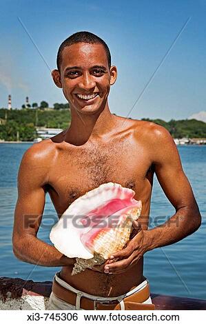 Young man posing with conch shell on Quay Granma Island, Cayo Granma, Santiago Bay, Santiago de Cuba, Cuba View Large Photo Image Stock Photograph - Young man posing with conch shell on Quay Granma Island, Cayo Granma, Santiago Bay, Santiago de Cuba, Cuba. Fotosearch