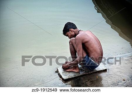Young man preparing a fish hook at the riverbank of the Ganges rives Varanasi, Benares, Uttar Pradesh, India View Large Photo Image Stock Photo - Young man preparing a fish hook at the riverbank of the Ganges rives Varanasi, Benares, Uttar Pradesh, India. Fotosearch