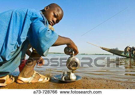 Young man preparing tea by Niger River, Segou, Mali View Large Photo Image Stock Photograph - Young man preparing tea by Niger River, Segou, Mali. Fotosearch