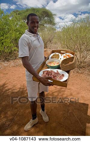 Young man presenting lunch in a Safari camp in Tansania, Africa View Large Photo Image Stock Image - Young man presenting lunch in a Safari camp in Tansania, Africa. Fotosearch