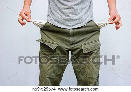 Young man pulling his pockets out to illustrate lack of money. View Large Photo Image Picture - Young man pulling his pockets out to illustrate lack of money.. Fotosearch