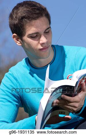 Young man reading a book outdoors View Large Photo Image Stock Photography - Young man reading a book outdoors. Fotosearch