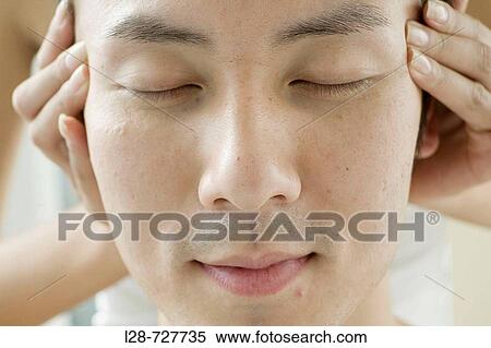 Stock Photography - Young man receiving head massage, eyes closed, close-up. Fotosearch