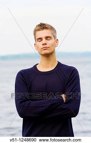 Stock Image - Young man relaxed with closed eyes by the sea. Fotosearch