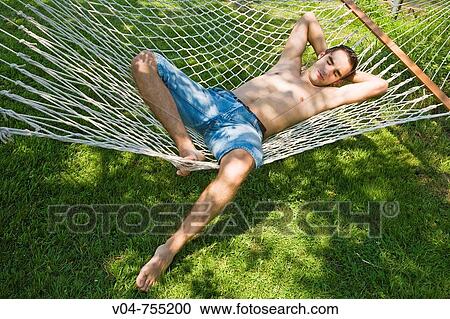 Stock Image - Young man relaxing and sleeping in a hammock outdoor. Fotosearch