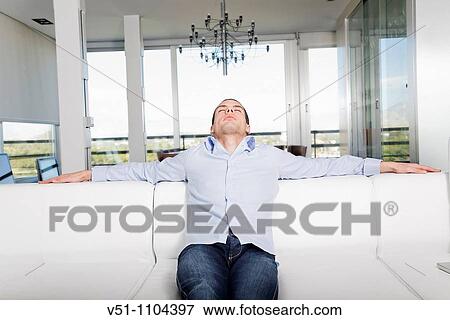 Young man relaxing at home after a hard day's work View Large Photo Image Stock Photo - Young man relaxing at home after a hard day's work. Fotosearch