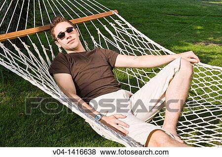 Young man relaxing in a hammock in the garden, Germany, Europe View Large Photo Image Stock Photo - Young man relaxing in a hammock in the garden, Germany, Europe. Fotosearch