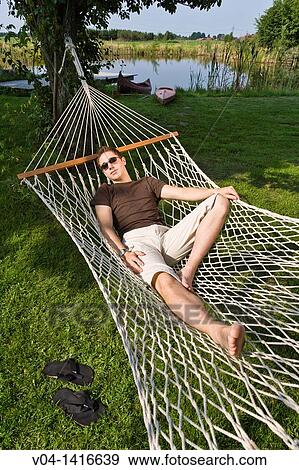 Young man relaxing in a hammock in the garden, Germany, Europe View Large Photo Image Stock Photo - Young man relaxing in a hammock in the garden, Germany, Europe. Fotosearch