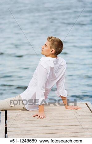 Young man relaxing in a pier by the sea View Large Photo Image Stock Photo - Young man relaxing in a pier by the sea. Fotosearch