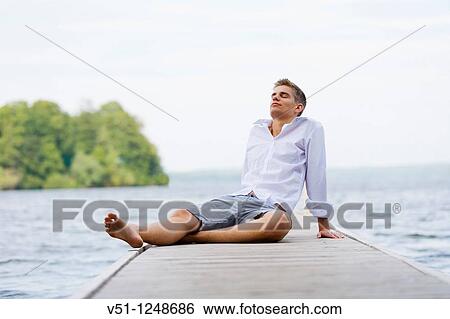 Young man relaxing in a pier by the sea View Large Photo Image Stock Photograph - Young man relaxing in a pier by the sea. Fotosearch