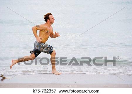 Young man running at the beach View Large Photo Image Stock Photo - Young man running at the beach. Fotosearch