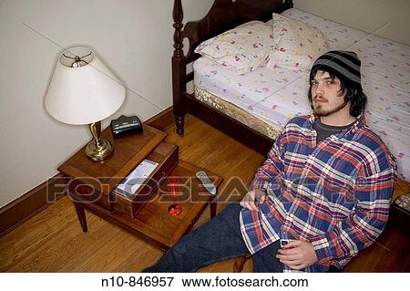 Young man sitting in his bedroom. Model and Property Released. View Large Photo Image Stock Photo - Young man sitting in his bedroom. Model and Property Released.. Fotosearch
