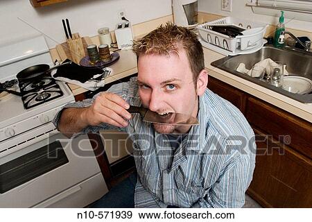 Young man sitting in his kitchen, holding a knife. View Large Photo Image Stock Photo - Young man sitting in his kitchen, holding a knife.. Fotosearch
