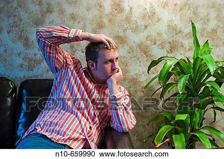 Young man sitting next to a plant. View Large Photo Image Stock Image - Young man sitting next to a plant.. Fotosearch