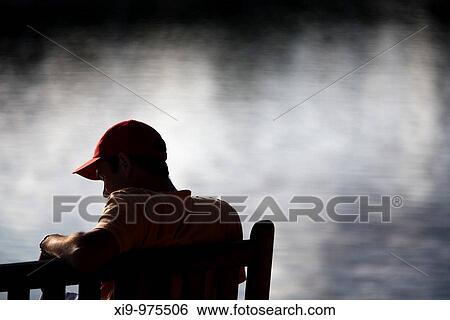 Young man sitting on a bench by the sea, Conleau island, town of Vannes, departament of Morbihan, region of Brittany, France View Large Photo Image Stock Photograph - Young man sitting on a bench by the sea, Conleau island, town of Vannes, departament of Morbihan, region of Brittany, France. Fotosearch