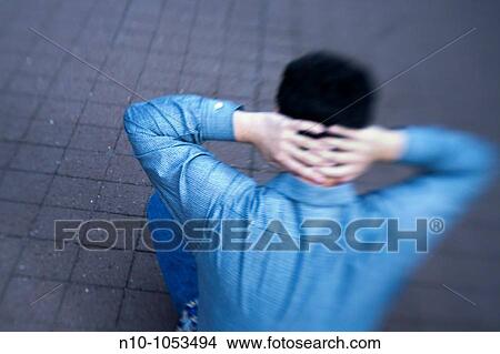 Picture - Young man sitting on a sidewalk. Fotosearch
