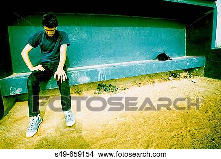 Picture - Young man sitting on football bench.. Fotosearch