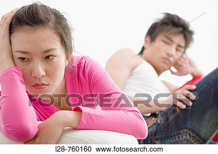 Young Man sitting on sofa, looking at distressed Woman View Large Photo Image Stock Image - Young Man sitting on sofa, looking at distressed Woman. Fotosearch