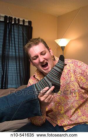 Young man sitting on the bed in his bedroom while holding onto a woman's foot. View Large Photo Image Stock Photography - Young man sitting on the bed in his bedroom while holding onto a woman's foot.. Fotosearch