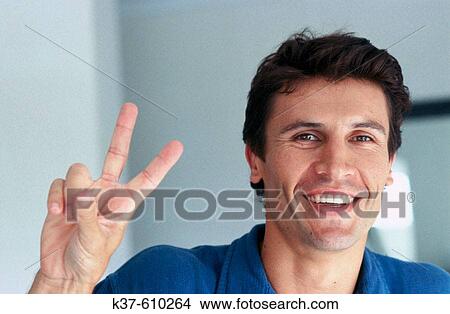 Young Man smiling & giving the Peace Sign View Large Photo Image Picture - Young Man smiling & giving the Peace Sign. Fotosearch