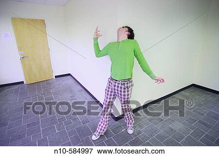 Stock Photo - Young man standing against a wall in the lobby of an office building.. Fotosearch