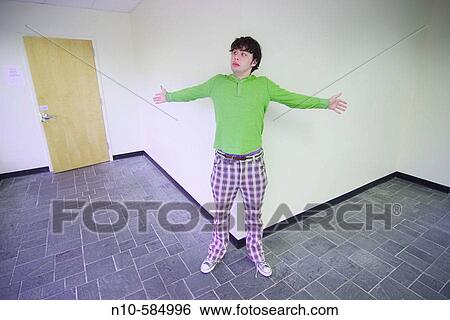 Young man standing against a wall in the lobby of an office building. View Large Photo Image Stock Photograph - Young man standing against a wall in the lobby of an office building.. Fotosearch