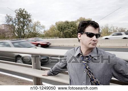 Young man standing by a highway View Large Photo Image Stock Image - Young man standing by a highway. Fotosearch