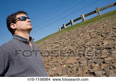Young man standing by a rock wall View Large Photo Image Picture - Young man standing by a rock wall. Fotosearch