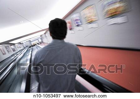 Young man standing on a moving walkway View Large Photo Image Stock Photo - Young man standing on a moving walkway. Fotosearch