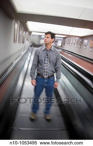 Young man standing on a moving walkway View Large Photo Image Stock Photography - Young man standing on a moving walkway. Fotosearch