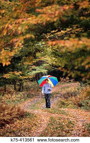 Young man walking with umbrella View Large Photo Image Stock Image - Young man walking with umbrella. Fotosearch
