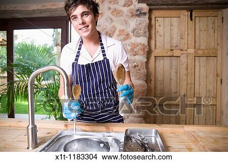 Young man Washing dishes. View Large Photo Image Picture - Young man Washing dishes.. Fotosearch