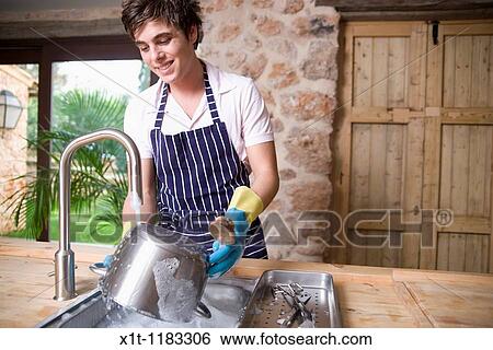 Stock Photograph - Young man Washing dishes.. Fotosearch