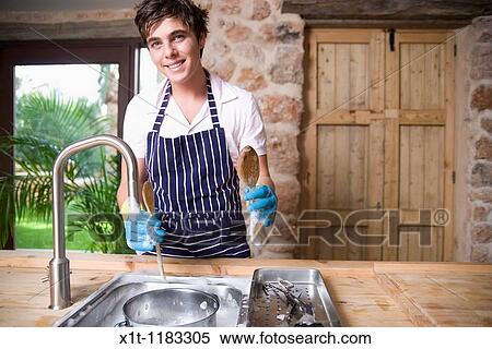 Stock Photography - Young man Washing dishes.. Fotosearch