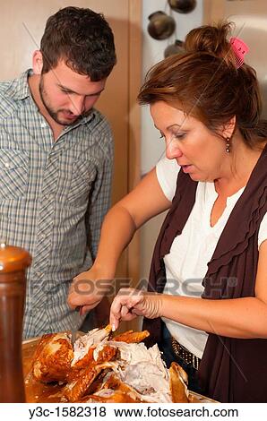 Young man watching his mother cooking and cutting meat off a turkey View Large Photo Image Stock Photo - Young man watching his mother cooking and cutting meat off a turkey. Fotosearch