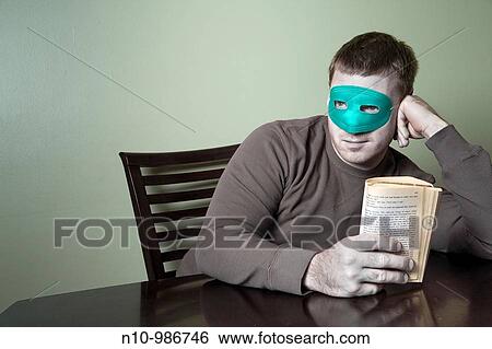 Young man wearing a mask and holding a book View Large Photo Image Stock Photograph - Young man wearing a mask and holding a book. Fotosearch