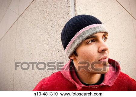 Young man, wearing a red sweatshirt and cap, standing in front of the corner of a building View Large Photo Image Stock Image - Young man, wearing a red sweatshirt and cap, standing in front of the corner of a building. Fotosearch