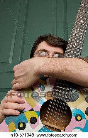 Stock Photo - Young man, wearing glasses, holding his guitar. Fotosearch