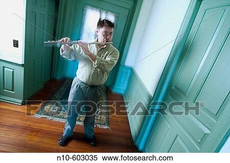 Young man, wearing glasses, playing a flute in the hallway of his house. View Large Photo Image Stock Photography - Young man, wearing glasses, playing a flute in the hallway of his house.. Fotosearch