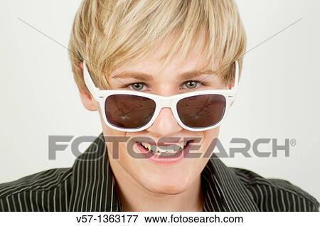 Young man wearing sunglasses, smiling and looking at the camera. Close view. View Large Photo Image Stock Photo - Young man wearing sunglasses, smiling and looking at the camera. Close view.. Fotosearch