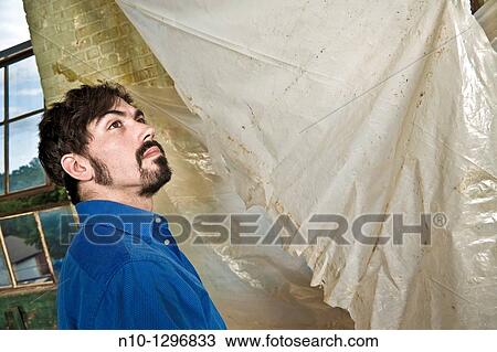 Stock Image - Young man with a mustache and beard in an old factory. Fotosearch