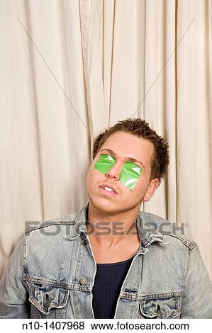 Young man with green tape over his eyes View Large Photo Image Stock Photo - Young man with green tape over his eyes. Fotosearch