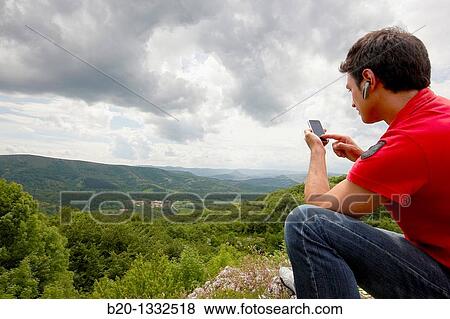 Young man with iPhone, Murguia, Alava, Euskadi, Spain View Large Photo Image Stock Photo - Young man with iPhone, Murguia, Alava, Euskadi, Spain. Fotosearch
