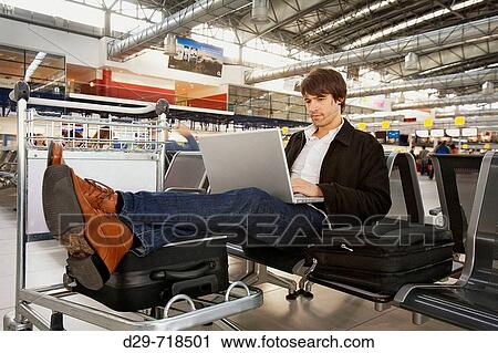 Young man with laptop at the airport View Large Photo Image Stock Image - Young man with laptop at the airport. Fotosearch