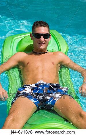 Young man with sunglasses on floating matress in the pool, Miramar, Florida, USA View Large Photo Image Stock Photo - Young man with sunglasses on floating matress in the pool, Miramar, Florida, USA. Fotosearch