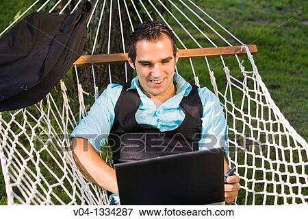 Young man working with his laptop in a hammock, Germany, Europe View Large Photo Image Stock Photo - Young man working with his laptop in a hammock, Germany, Europe. Fotosearch